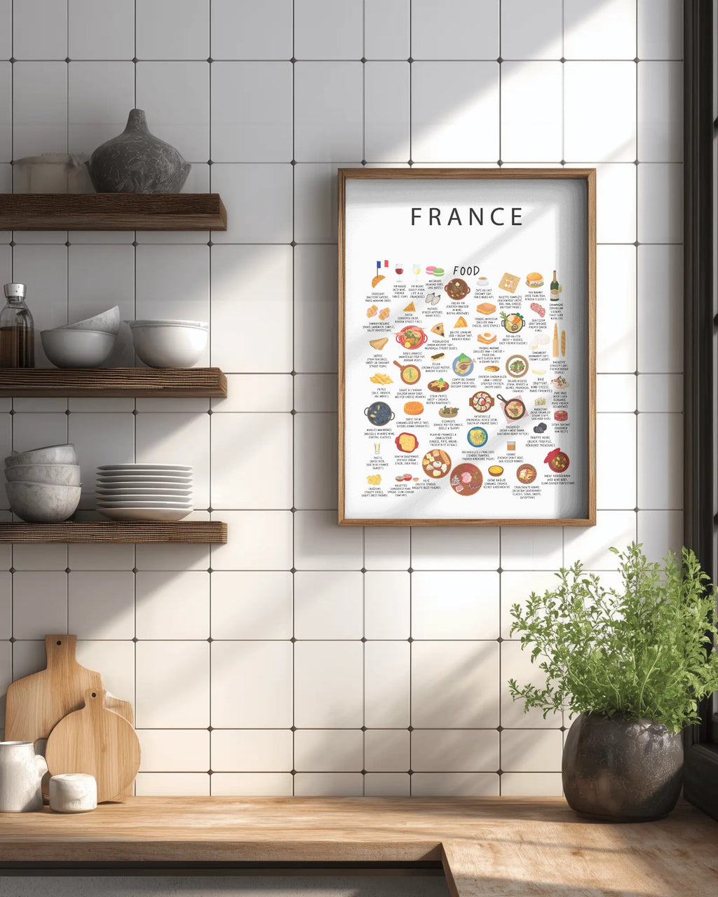 Framed white France food poster hanging on a white tiled wall above a wooden kitchen counter with floating shelves and a potted plant.