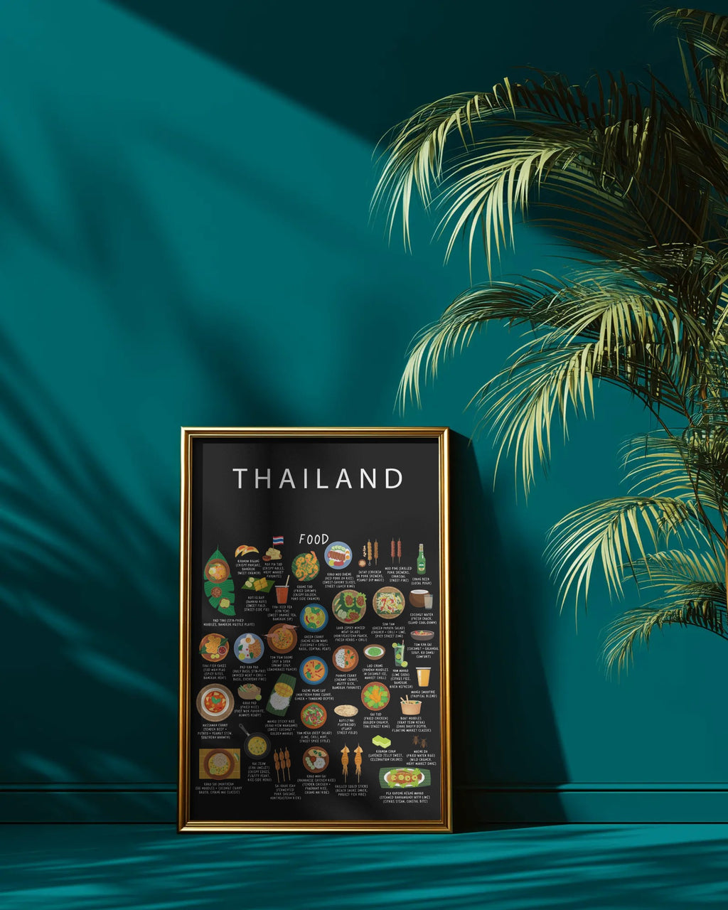A black Thailand food poster in a gold frame leans against a deep teal wall beside a leafy palm casting shadows.