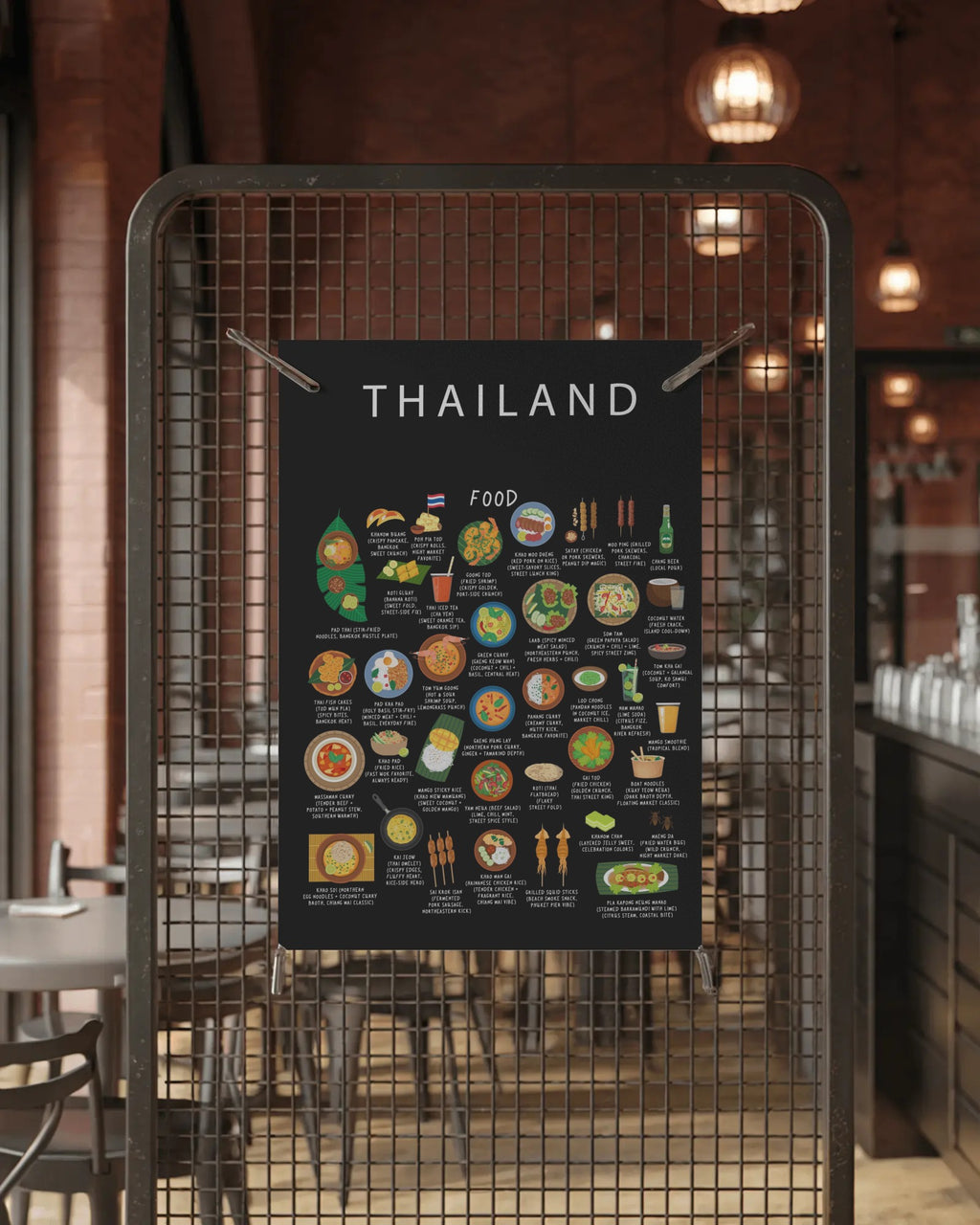 A black Thailand food guide poster clipped onto a wire mesh partition in a dimly lit restaurant with warm pendant lights.