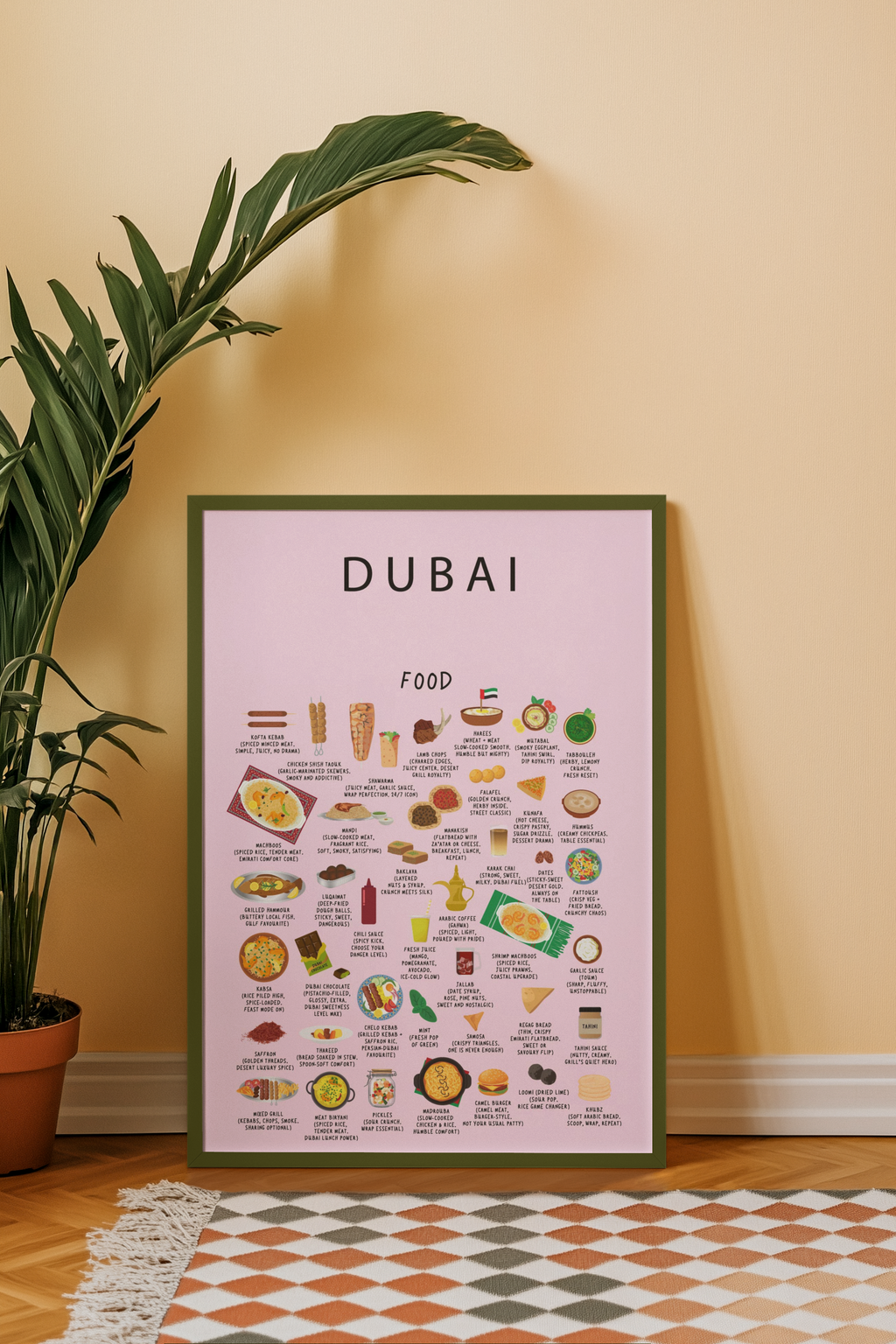 A framed pink Dubai food poster rests on a wooden floor beside a potted houseplant and a checkered rug against a beige wall.